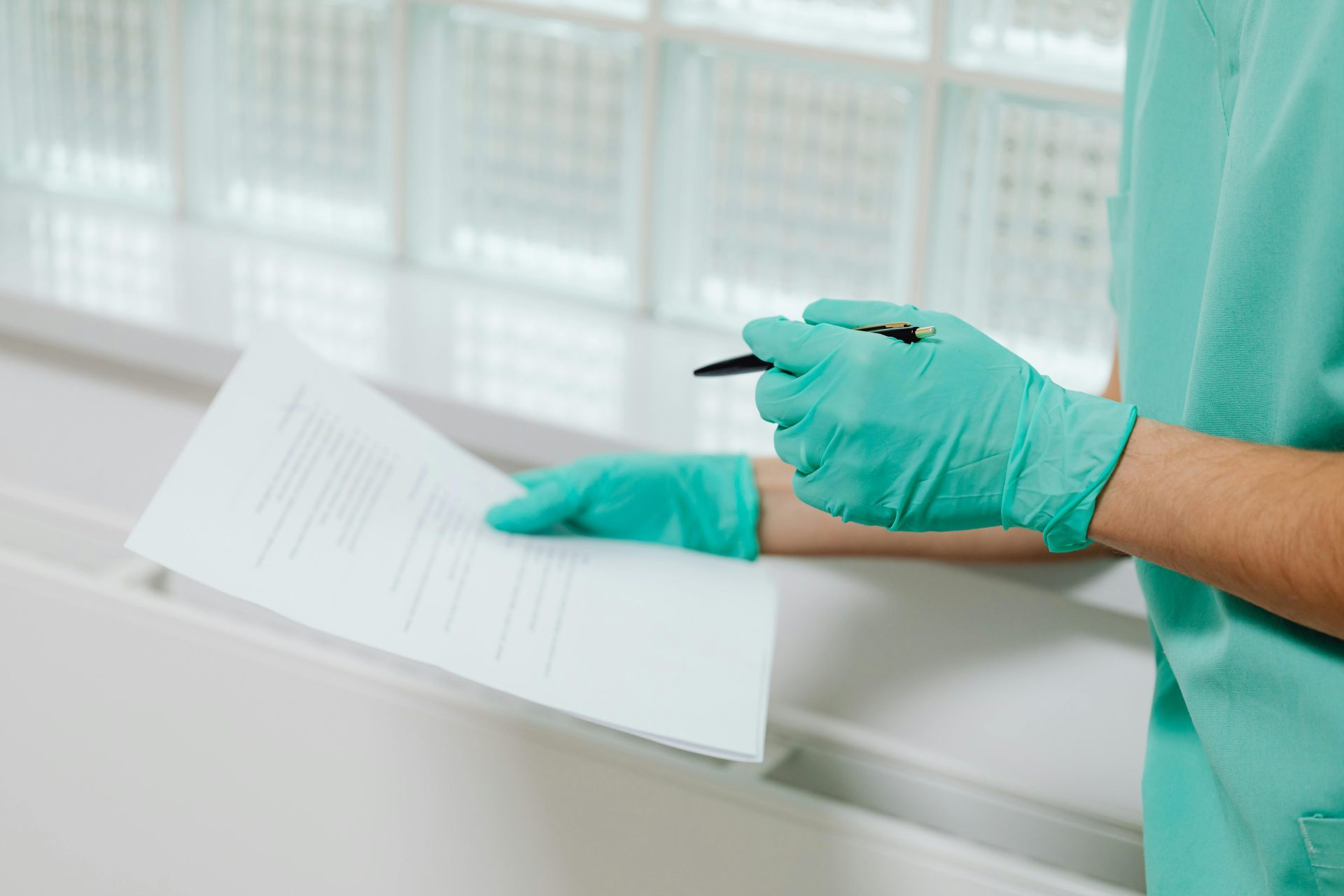 Close-up of a healthcare professional in gloves holding and reading a medical document indoors.